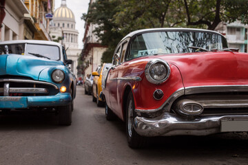 Obraz na płótnie Canvas Old car on streets of Havana with colourful buildings in background. Cuba