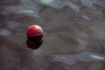 London, UK - September 17th 2021: a round red buoy drifting on the water