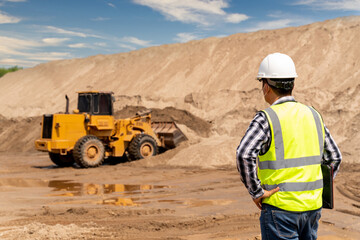 Civil Engineer inspecting work of Yellow Excavator working at sandpit. sand industry.