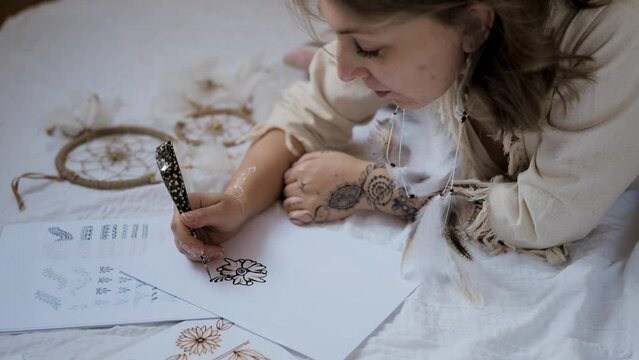 Young woman practice henna or mehndi designs on paper