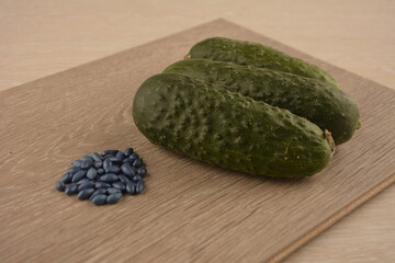 Green cucumbers lie on the table and hybrid seeds next to them.