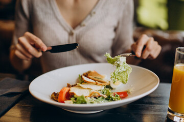 Young woman eating healthy breakfast with juice in a cafe close up