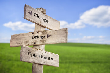 Change brings opportunity text quote on wooden signpost outdoors on green field with blue sky.