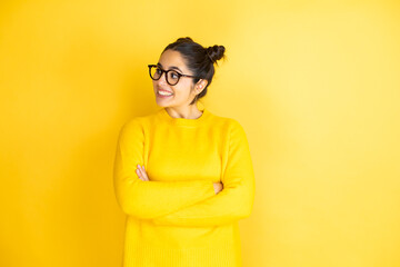 Young beautiful woman wearing casual sweater over isolated yellow background looking to side, relax profile pose with natural face and confident smile.