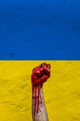 Wounded hand with the raised fist with Ukrainian flag colours as a sign of resistance to the Russian bombing. War Russia / Ukraine concept.