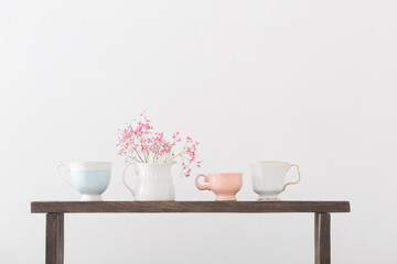pink gypsophila and cups on  wooden shelf on  white background
