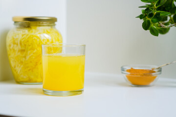 Fermented cabbage with turmeric. Cabbage kvass. Pickling vegetables without salt. Fermentation. Vitamin treatment and nutrition. Organic turmeric powder and green leaves of houseplant in a frame.