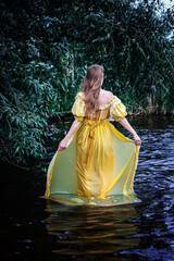 woman in yellow historic dress standing in the water