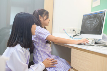 Female dentist explaining teeth x-ray to a little girl in dental clinic, teeth check-up and Healthy teeth concept