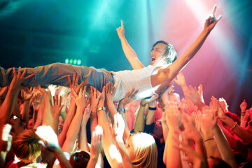 A young man cheering as he crowd surfs at a concert. This concert was created for the sole purpose of this photo shoot, featuring 300 models and 3 live bands. All people in this shoot are model