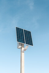 A street lighting system consisting of a solar panel and an LED lamp on blue sky background. Solar...