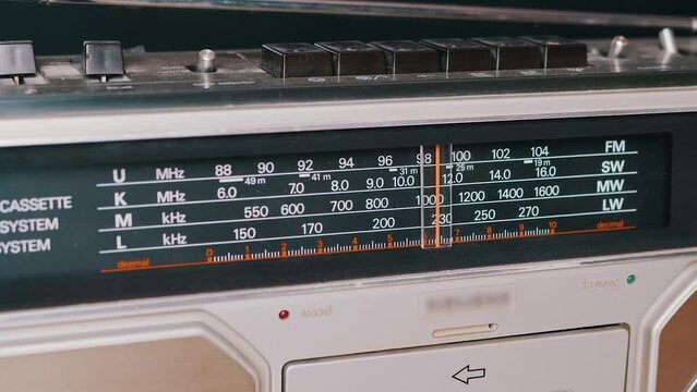 Tuning the Frequency, Searching Wave on an Old Vintage Analog Radio. Search for a music radio station on a dial scale on panel of a short-wave portable FM receiver, player, tape recorder 80s, 90s.