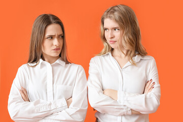 Portrait of displeased young sisters on color background