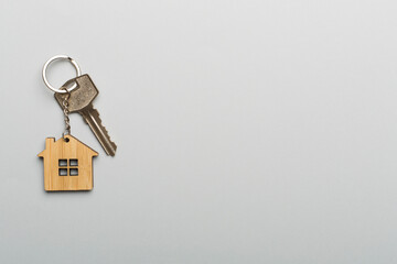 Keys with house-shaped keychain on color background