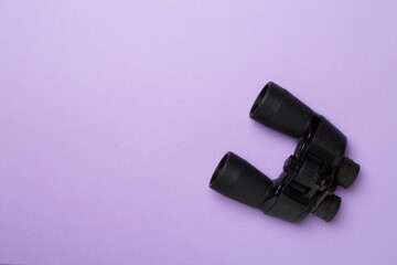 Black binoculars on color background. Top view