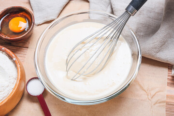 Fototapeta na wymiar Raw batter in bowl with whisk on table