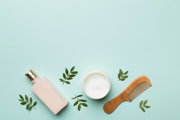 Shampoo and mask with herbal extract and comb on color background, top view