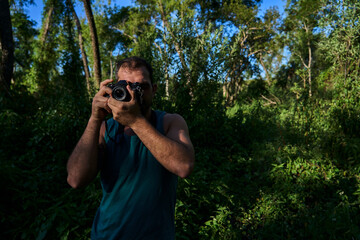 young man photographing in nature with vintage camera