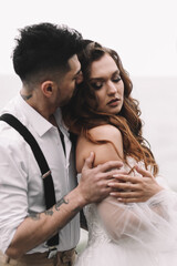 The bride and groom in wedding dresses hug and walk together along the sea in nature on an outdoor trip. Husband and wife in love spend their honeymoon. Selective focus