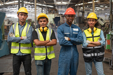 Group of diverse Engineer and workers wear safety vests with helmets standing cross arm on machine...