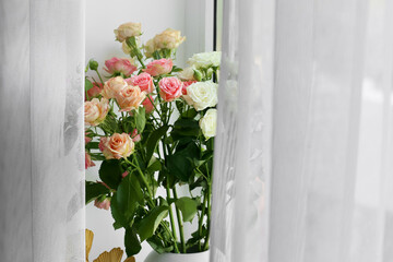 Vase with beautiful roses near window