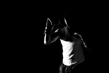 Young man practicing shadow boxing over black background. Black and white high contrast image....