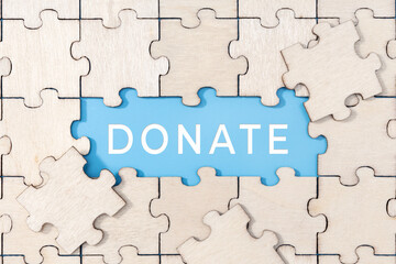 Donate word on blue background surrounded by puzzle pieces