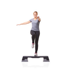 Improving her health one step at a time. A smiling young woman doing aerobics on an aerobic step...
