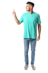 Fototapeta premium Handsome young man in stylish t-shirt pointing at something on white background