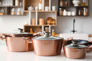 Shiny cooking pots on table in light kitchen