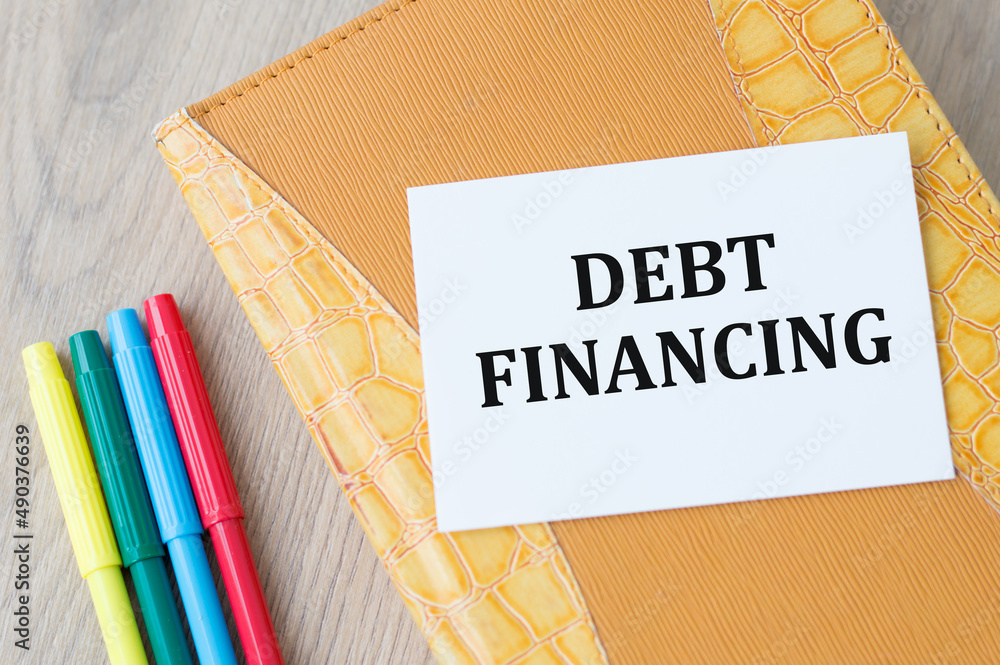 Poster debt financing text on a card on a notebook on a wooden table