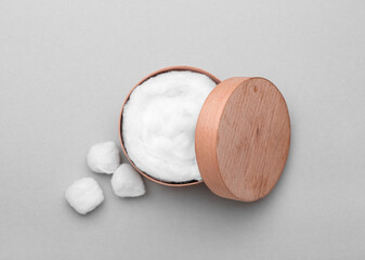 Wooden box with soft cotton wool on light background