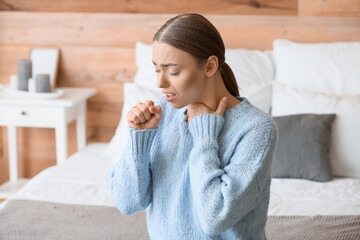 Ill coughing young woman with sore throat at home