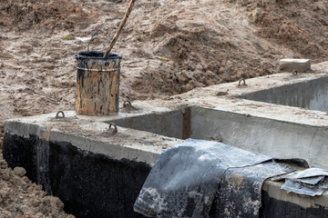 Installation of a reinforced concrete well for water supply and sewerage at the construction site. Well rings with cast iron hatch and construction tool.