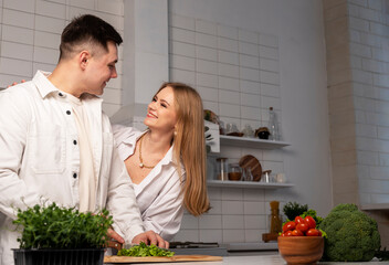Happy couple cooking at home. Copy space. Man making fresh vegetables salad in white modern kitchen in scandi style. High quality photo
