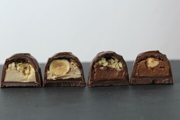 chocolate corus candies in section with a white chocolate filling with hazelnuts peanuts praline ganache on a gray background with space for text and copyspace. Day chocolate sweets without diet