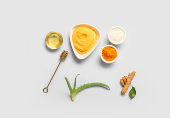 Composition with turmeric mask in bowl, powder and honey on grey background