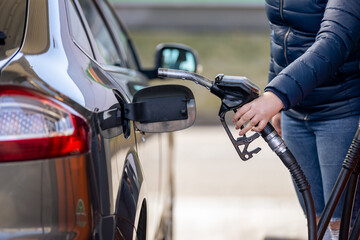 Process of refueling a car fill with petrol fuel at the gas station, pump filling fuel nozzle in fuel tank of car, high price of petrol and oil fuel, economic concept