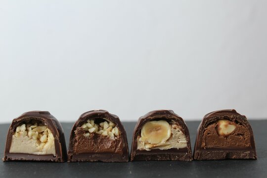 chocolate corus candies in section with a white chocolate filling with hazelnuts peanuts praline ganache on a gray background with space for text and copyspace. Day chocolate sweets without diet