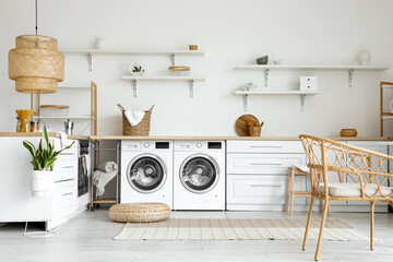 Interior of light kitchen with washing machines, laundry basket and white counters