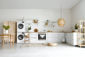 Interior of light kitchen with washing machines, white counters and shelves