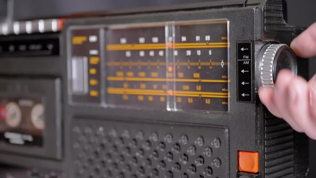 Female Fingers Adjusting the Frequency on an Old Vintage Analog Receiver. Search for a music radio station on a dial scale on panel of a short-wave portable FM radio, player, tape recorder 80s, 90s.