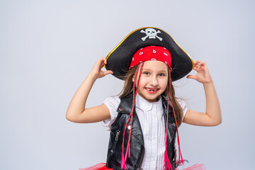 Portrait of a naughty little girl in a pirate costume, standing on a whrite background, A girl is...