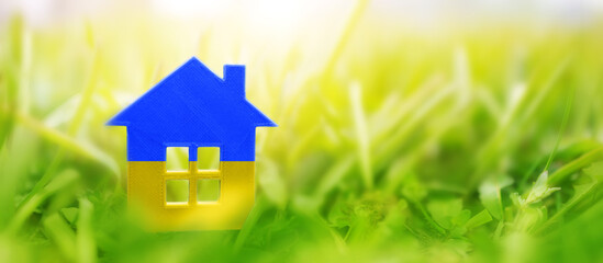Naklejka premium House model on the grass in urainian flag colours