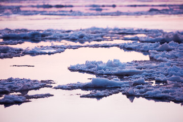 Ice drift on calm water in river during the sunset in spring