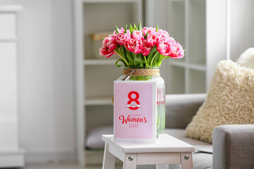 Bouquet of tulips and greeting card with text HAPPY WOMEN'S DAY on stepladder stool in room