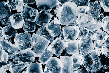 Pieces of crushed pure ice cubes on black background. Refreshing background.