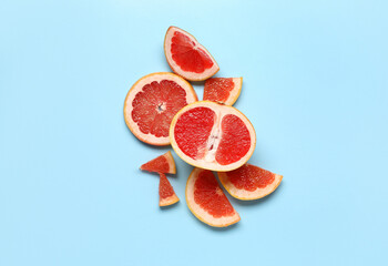 Slices of tasty ripe grapefruit on blue background