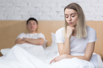 Frustrated woman sitting in bed unhappy asian man, at home, under blanket