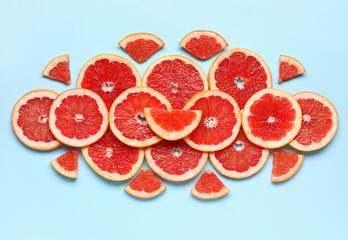 Slices of tasty ripe grapefruit on blue background